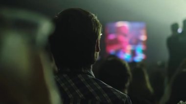 Zıplayan, el sallayan, fotoğraf çeken ya da canlı müzik konserinin videolarını açık hava festivalinde akıllı telefonlardan çeken insanların siluetleri. Parlak renkli sahne ışığı.