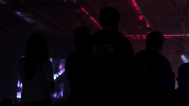 オープンエアフェスティバルで スマートフォンでライブミュージックコンサートのビデオをジャンプ 録画する人々のシルエット 明るい多彩な段階の照明 — ストック動画