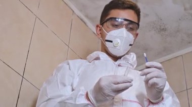 Küf temizleme, küflü banyo ve küflenmek için kimyasallar sıkan profesyonel koruyucu takım elbiseli bir adam.