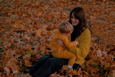 Bir anne ve oğlu birlikte güzel vakit geçirir, sonbahar parkında oynarlar, ikisi de sarı giyinir. Renkli yaprakların arasında, neşeli anları paylaşıyorlar, taze havada yankılanan kahkahalar..