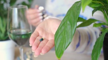 Temel vitaminlerle sabah rutinini geliştir! Bir kadın Omega ve B vitaminleri tutuyor, sağlık ayinlerine odaklanıyor. Bağışıklık sistemini güçlendir ve genel refahını arttır.