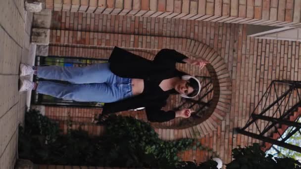 헤드폰을 착용하는 소녀는 옥외에서 즐겁게 응원과 긍정적 진동을 퍼뜨립니다 거리에서 — 비디오