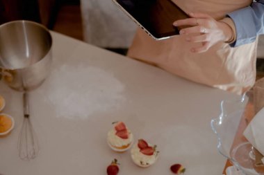 Kadın bir pasta şefi ev yapımı pişirmeyi temsil eden siparişleri yönetmek için bir tablet tutuyor. Glütensiz ve şekersiz ürünlerle küçük ölçekli, çevre dostu pişirmenin özünü tecrübe edin, sağlıklı beslenmeyi teşvik edin..
