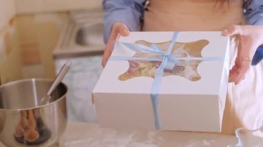 Bir kadın pasta şefi bir kutuya kek paketliyor. Ev yapımı, küçük işletme, çevre dostu üretim, glütensiz, şekersiz, sağlıklı yeme alışkanlıklarını teşvik eden.