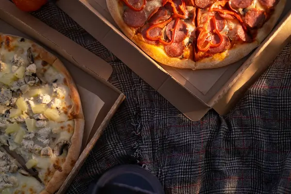 Pizza rests on a picnic blanket, epitomizing a spring picnic scene with a delicious pizza spread.