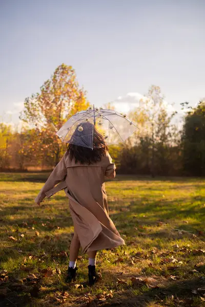 Μια Γυναίκα Μπεζ Παλτό Τρέχει Στο Πάρκο Κρατώντας Μια Ομπρέλα — Φωτογραφία Αρχείου