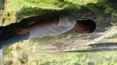 Adam oturmuş, şelalenin güzelliğine hayret ediyor. Çevre turizmi, doğa gezileri ve doğal rezervleri ve parkları keşfetmek için mükemmel..