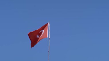 Türk bayrağı, ulusal gurur ve vatanseverliği simgeleyen açık mavi gökyüzüne doğru dalgalanıyor. Seyahat ve kültürel kavramlar için mükemmel..