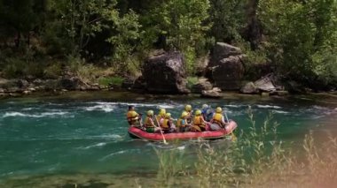 Can yelekli bir grup insan bir dağ nehrinde sallara biniyor. Aktif dinlenme, dağ nehirlerinde rafting, turlar ve dinlenme alanlarına geziler. Sıra dışı turizm.