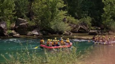 Can yelekli bir grup insan bir dağ nehrinde sallara biniyor. Aktif dinlenme, dağ nehirlerinde rafting, turlar ve dinlenme alanlarına geziler. Sıra dışı turizm.
