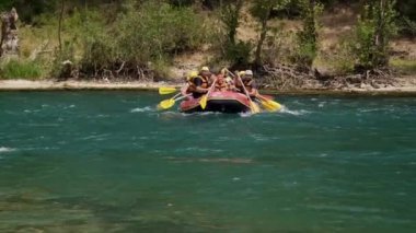 Can yelekli bir grup insan bir dağ nehrinde sallara biniyor. Aktif dinlenme, dağ nehirlerinde rafting, turlar ve dinlenme alanlarına geziler. Sıra dışı turizm.