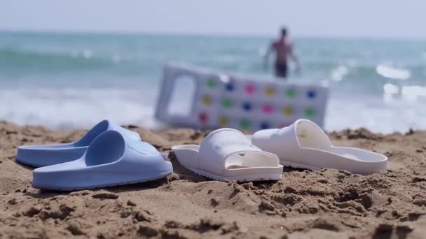 海滨的海滩凉鞋 海浪冲击着黄色的沙滩 海滩鞋类和配件的销售 旅游胜地和海滩 — 图库视频影像