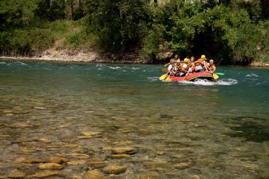 Can yelekli bir grup insan bir dağ nehrinde sallara biniyor. Aktif dinlenme, dağ nehirlerinde rafting, turlar ve dinlenme alanlarına geziler. Sıra dışı turizm.