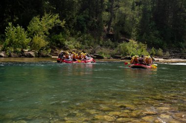 Can yelekli bir grup insan bir dağ nehrinde sallara biniyor. Aktif dinlenme, dağ nehirlerinde rafting, turlar ve dinlenme alanlarına geziler. Sıra dışı turizm.