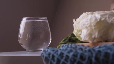 Bir bardak su, sağlıklı bir yaşam tarzını destekleyen sabah ayinlerinin bir parçası olarak masanın üzerinde duruyor. Limon suyu, lif emme, düzgün beslenme ve takviyeler..