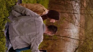 Bir kız ve bir adam parkta dolaşırken akıllı telefonlarıyla selfie çekiyorlar. Turizm hizmetleri ve seyahat, turist fotoğrafçılığı ve fotoğraf turları, göl kenarı otelleri ve tatil beldeleri.