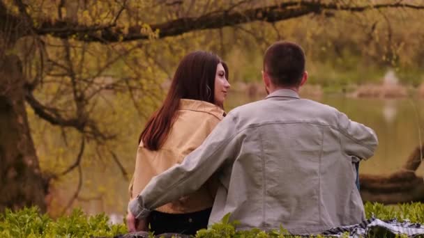 一对年轻夫妇坐在湖边 欣赏美丽的风景 大自然中的露营 代表着青少年的爱和友谊 充满着感情和感情 — 图库视频影像
