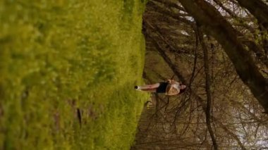 Genç bir kız ormanda gezici fitness uygulamalarını ve sağlıklı bir yaşam tarzını tanıtarak koşuyor. Gençlerin spor kıyafetleri ve ayakkabıları ile maceralı açık hava aktiviteleri için gerekli malzemeler.