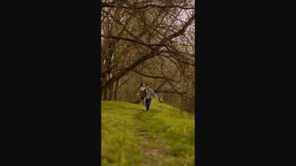 若いカップルが森の中を走り カメラに戻り 思春期の愛 十代のファッション そして最初のデートを思い出させる森の散歩を披露します — ストック動画