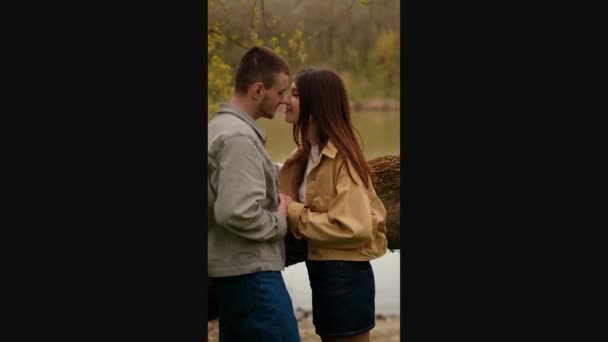若い愛と友情 十代のカップルが湖に抱擁し 最初の感情とキスを表現しています 最初のデートとロマンチックなミーティングスポットの本質をキャプチャ ティーンズの服ブランドと一緒に — ストック動画