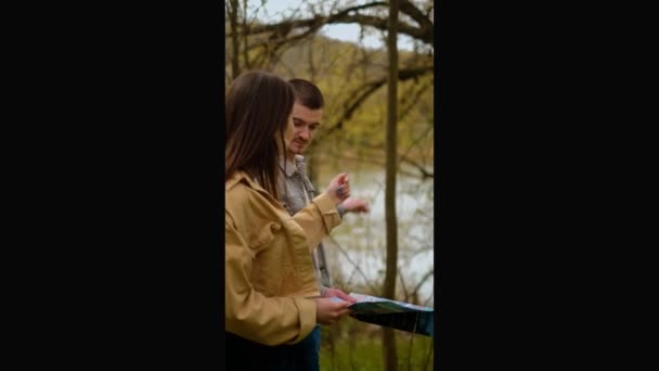 一个男人和一个女孩手里拿着地图在森林里导航应用程序 地理定位服务 旅行社 导游和景点 — 图库视频影像