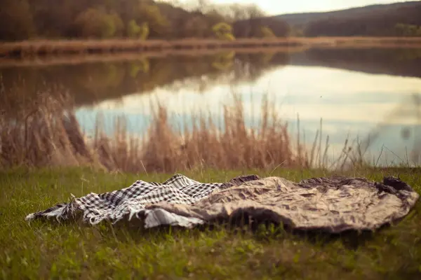 森林地帯の湖の景色 ピクニックのための水の端に敷かれた毛布 — ストック写真