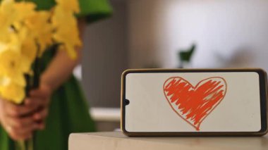 Bir buket çiçek tutan ellerin yakın çekimi; ön planda, üzerinde 