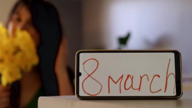 Bir buket çiçek tutan ellerin yakın çekimi; ön planda, üzerinde 