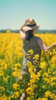 Sarı bir tarlanın yanındaki orman yolunda hasır şapkalı ve çantalı bir kadının arka planı açık hava pikniklerini ve aktif bir yaşam tarzını destekliyor..