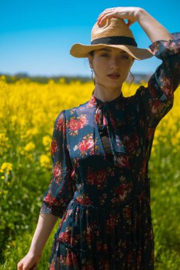 Hasır şapka ve çiçek buketi, yaz aksesuarları, plaj ürünleri, tatil malzemeleri veya tatil hizmetleri ile tarladaki genç kadın yaz rahatlama ve konfor ortamı yaratıyor..