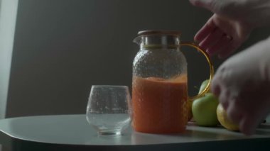 Kadın bardağa taze havuç ve elma suyu dolduruyor. Sağlıklı bir yaşam için vitaminli içecek..