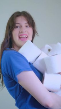 Mutlu kız elinde bir sürü tuvalet kağıdı tutuyor, ev eşyaları için dağıtım hizmetlerini destekliyor, kolaylık ve zaman tasarrufu vurguluyor, dikey video, sstkVertical