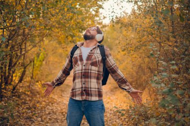 Gömlekli sakallı adam, ormanın önünde kollarını açmış duruyor. Ormanda kollarını açmış beyaz erkek turist. Boşluğu kopyala.