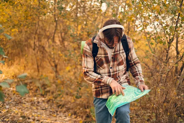 stock image A man in headphones engages in educational programs or audio tours, using a map to understand the geography and history of the area.