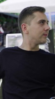 Genç beyaz adam terasta mojito içiyor, ambiyansı vurguluyor ve içkileri tazeliyor, şehir rehberleri yerel kafeleri ve mutfağı vurguluyor..