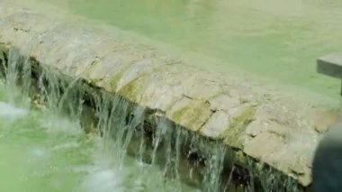 Mavi suların taştan basamakların üzerine döküldüğü bir çeşmenin yakın çekimi, doğa ve mimari ortamda park gezintilerinin ve rahatlamanın faydalarını teşvik eder..