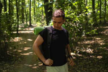 A man with a backpack exercises in the forest, outdoor fitness featuring active hiking with a backpack. clipart