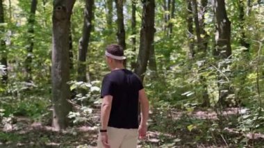 Orman ortamında eğitim programı yürütüyor. Bir adam parkta koşuyor, kameraya gülümsüyor, doğanın sükuneti ve huzurunun tadını çıkarıyor..