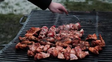 Açık ateşte et pişiren, online ve çevrimdışı atölyelerde barbekü teknikleri ve yemek tarifleri sergileyen bir adamın ellerine yakın çekim..