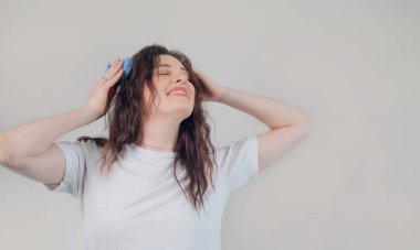 Kafa masajı aleti kullanan mutlu bir kız statik elektriği azaltıyor ve saçları daha düzgün ve daha kontrol edilebilir yapıyor..