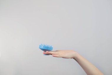 Evde saç bakımı, elinde silikon fırça ya da kafa masajı aleti olan bir kadın, masaj baş ağrısı ve migreni azaltabilir..