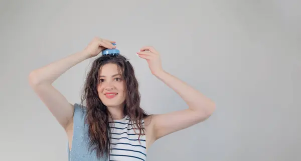 stock image Portrait of a beautiful young girl with long dark hair, applying hair growth oil with a pipette, and massaging her scalp with a brush.