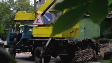 Büyük ağaç kütükleri toplayan sarı vinç, doğal afetlerden sonra belediye temizlik işi.