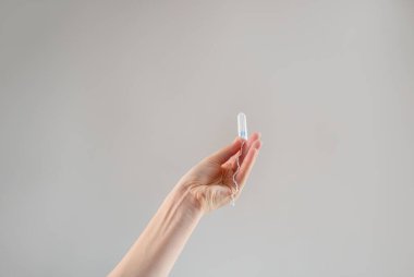 Bir kadının eli bej arka planda tampon tutuyor, kadın sağlığını, hijyeni, konforu ve sürdürülebilir çevre dostu ürünleri teşvik ediyor..