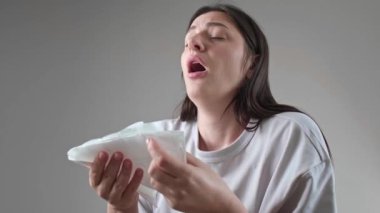 Burun tıkanıklığıyla boğuşan bir kadın, burnunu mendille siliyor, soğuk ve alerji için mevsimsel ilaçlar..