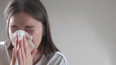 Burnu mendille kaplanırken hapşıran bir kadın alerjik reaksiyon gösteriyor..