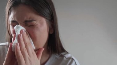 Burun tıkanıklığıyla boğuşan bir kadın, burnunu mendille siliyor, soğuk ve alerji için mevsimsel ilaçlar..