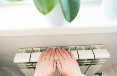 Isıtma mevsiminde elektrikli ısıtıcıyı ısıtan kadın, kış mevsiminde sıcak ve rahat bir atmosfer yaratıyor..