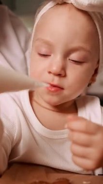 Bir çocuk, çocuklarla yemek pişirmenin eğlencesini vurgulayarak, hamur işi yaparken, boru torbasından krema yemekten zevk alır..