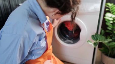 Ev hanımı çamaşır yıkamaya, çamaşır yıkama sırasında arka planda davul çevirerek evde kuru temizleme yapmaya başlıyor. Yüksek kalite 4k görüntü